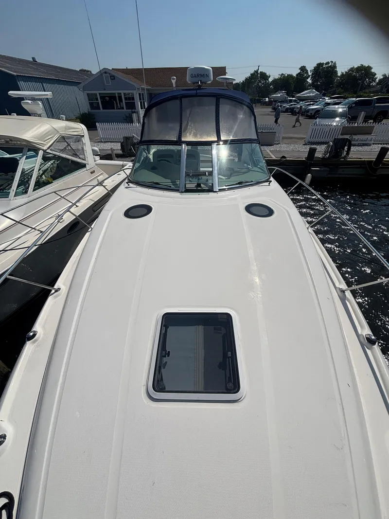 Slide: The Image of 2004 Sea Ray 320 Sundancer docked, showcasing sleek deck design and windshield. - 43