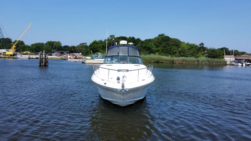 Slide: The Image of 2004 Sea Ray 320 Sundancer boat on calm water, surrounded by greenery and docks. - 9