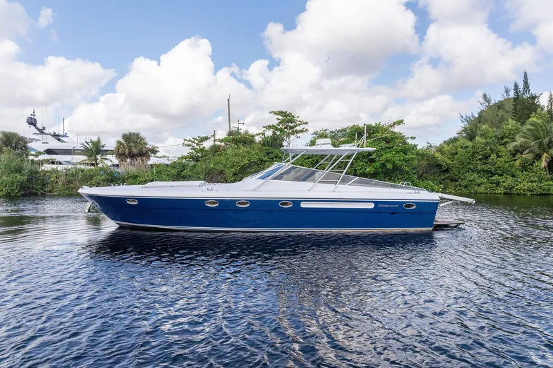 The Image of Blue 1995 Itama 46 yacht on a serene waterway, surrounded by lush greenery. - 0
