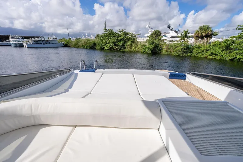 Slide: The Image of Luxury Itama 46 yacht deck with sunbed, surrounded by serene water and lush greenery, 1995 model. - 11