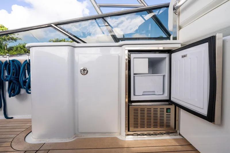 Slide: The Image of Itama 46 yacht (1995) with open mini fridge on deck, blue ropes, and glass railing. - 18