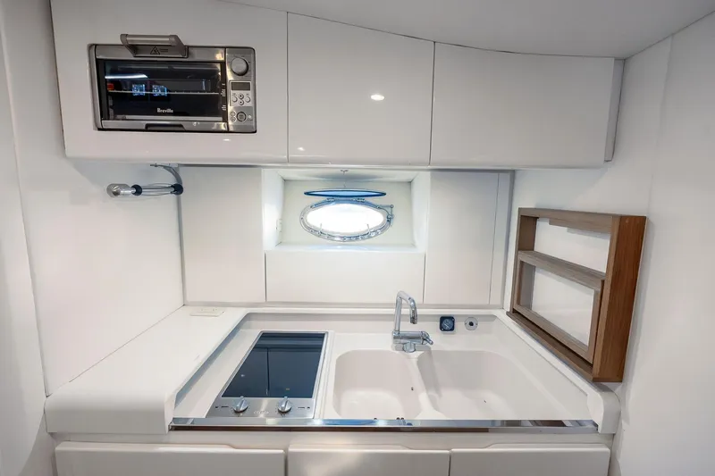 Slide: The Image of Compact kitchen area in a 1995 Itama 46 yacht with modern appliances and porthole window. - 26