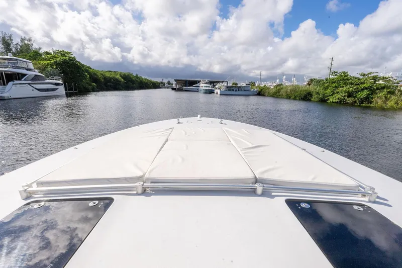 Slide: The Image of Bow view of 1995 Itama 46 yacht on a serene waterway under cloudy skies. - 7