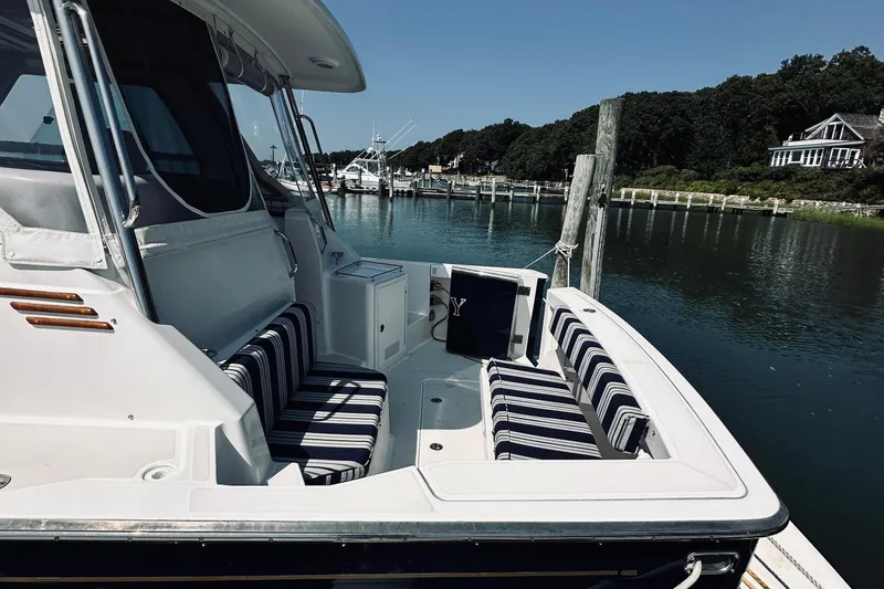 Slide: The Image of 2007 Sabreline 34 Express boat docked, featuring striped seating and scenic waterfront view. - 10