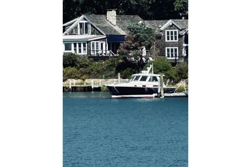 Slide: The Image of 2007 Sabreline 34 Express yacht docked near charming waterfront homes. - 2