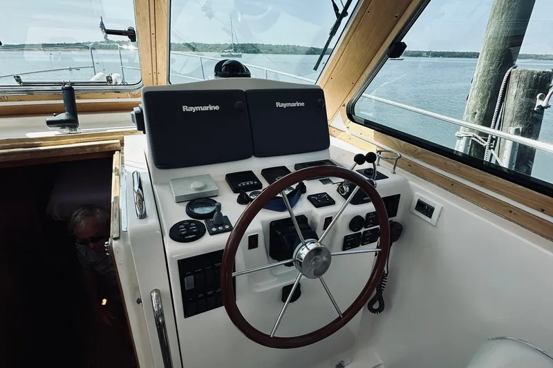 Slide: The Image of 2007 Sabreline 34 Express helm with Raymarine electronics, wooden steering wheel, and scenic water view. - 28