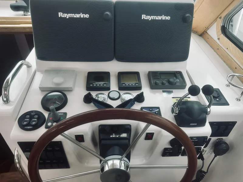 Slide: The Image of 2007 Sabreline 34 Express helm with Raymarine navigation equipment and wooden steering wheel. - 29