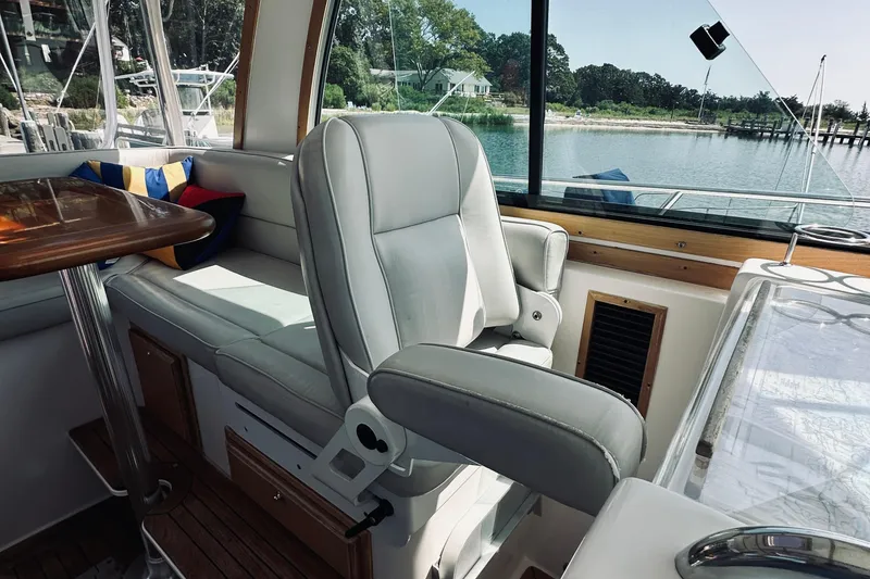 Slide: The Image of 2007 Sabreline 34 Express interior with helm seat and table, overlooking serene waterfront. - 39