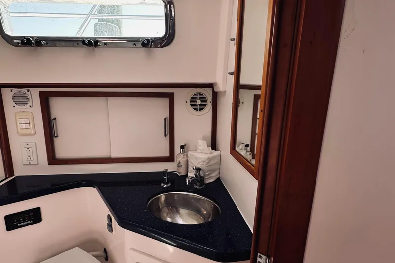 Slide: The Image of 2007 Sabreline 34 Express yacht bathroom with sink, mirror, and storage cabinets. - 64