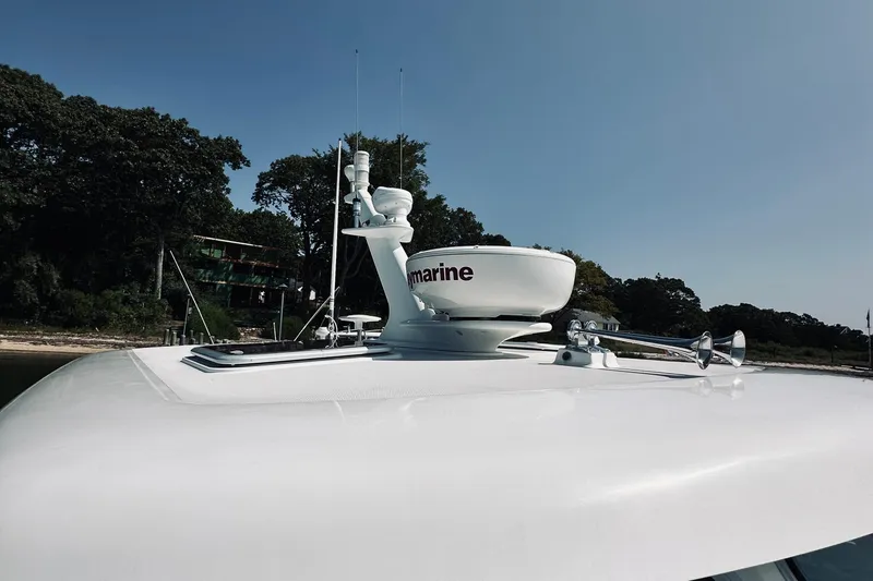 Slide: The Image of 2007 Sabreline 34 Express yacht with radar equipment, docked near a wooded shoreline. - 99