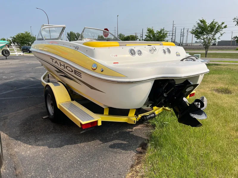 Slide: The Image of 2006 Tahoe Q4 boat on yellow trailer, parked on grass near pavement. - 5