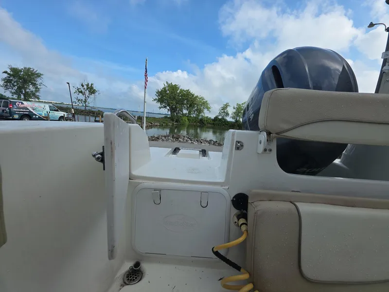 Slide: The Image of 2018 NauticStar 22 XS Offshore boat interior with motor, docked by a scenic lake. - 13