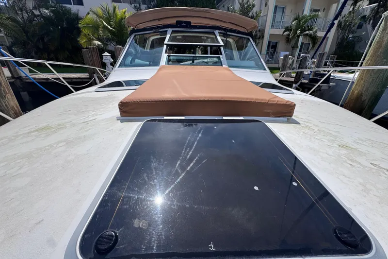 Slide: The Image of 2001 Tiara Yachts 3100 Open boat deck with sun pad and hatch, docked near palm trees. - 31