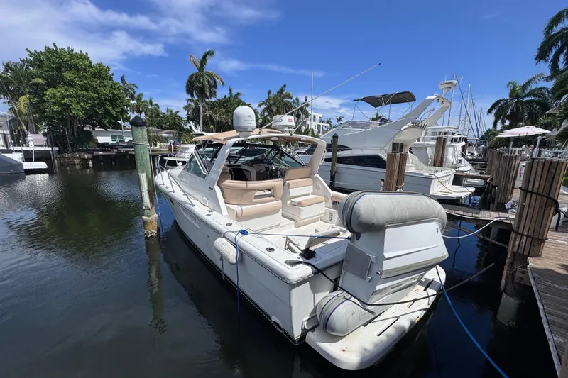 Slide: The Image of 2001 Tiara Yachts 3100 Open docked in a marina, surrounded by palm trees and clear skies. - 8