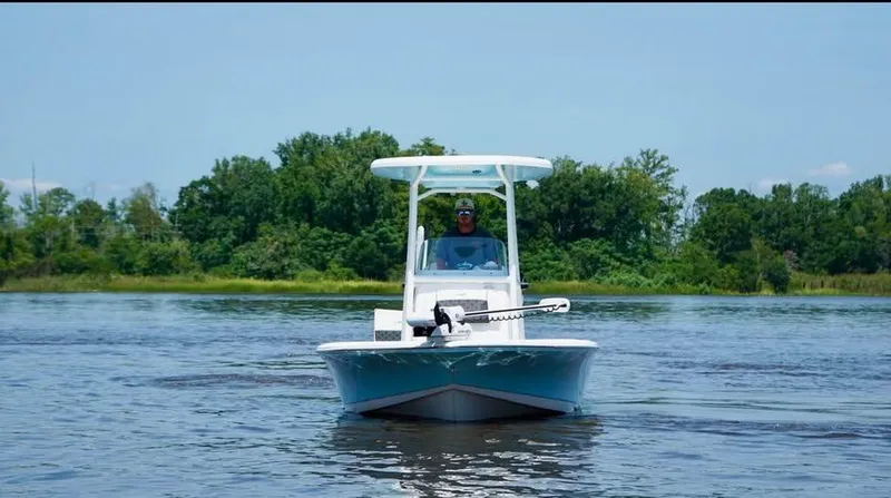 Slide: The Image of 2023 Tidewater 2110 Bay Max boat on calm water with lush green background. - 4