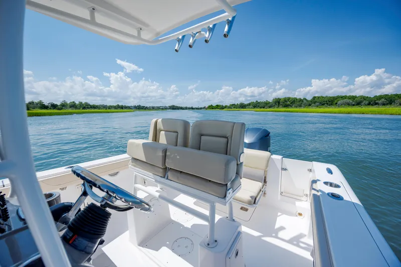 Slide: The Image of 2018 Pursuit C 238 Center Console boat on a serene waterway under a clear blue sky. - 19