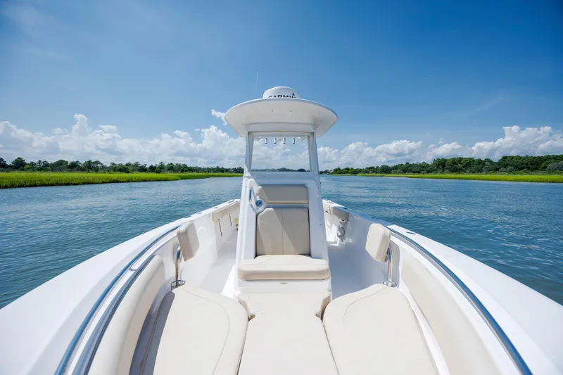 Slide: The Image of 2018 Pursuit C 238 Center Console boat on a serene waterway under a clear blue sky. - 24