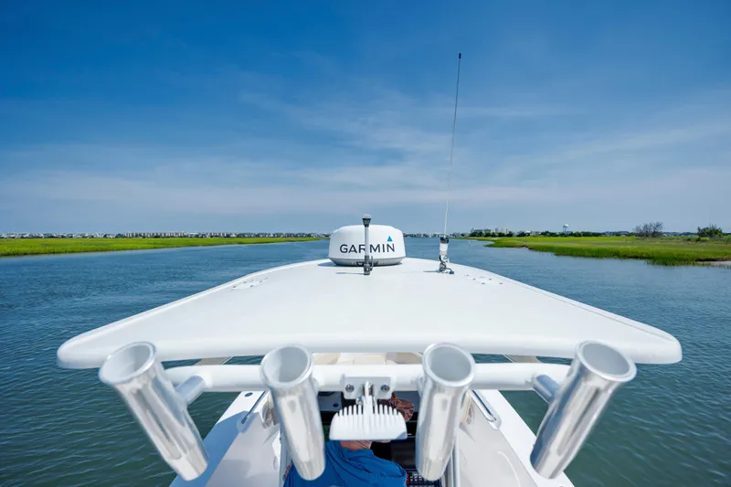 Slide: The Image of 2018 Pursuit C 238 Center Console boat navigating a serene waterway under a clear blue sky. - 26
