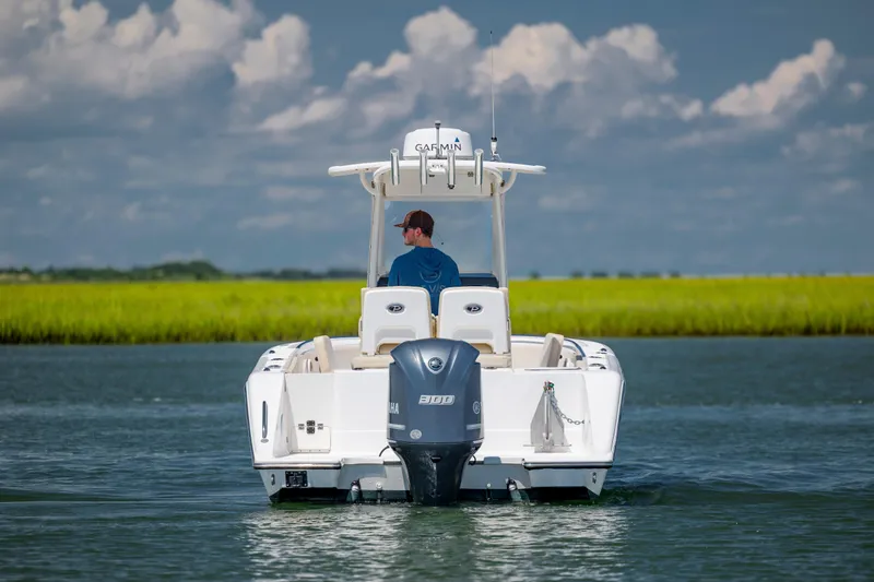 Slide: The Image of 2018 Pursuit C 238 Center Console boat on water, with scenic grassy shoreline. - 4