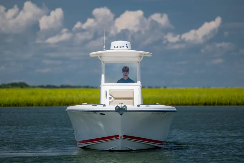 Slide: The Image of 2018 Pursuit C 238 Center Console boat on calm water, under a cloudy sky. - 8