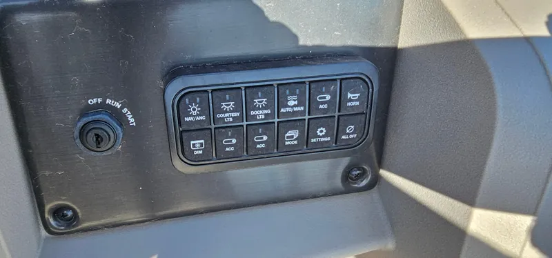 Slide: The Image of Control panel of 2024 Sun Tracker SportsFish 20 DLX with various switches and ignition. - 13