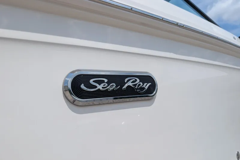 Slide: The Image of 2025 Sea Ray SDX 290 boat emblem on white hull under blue sky. - 34
