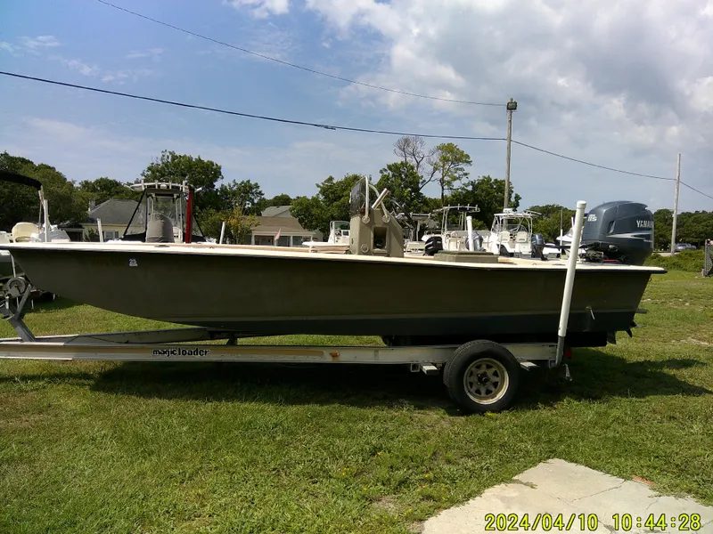 Slide: The Image of 2002 Intruder 20 Skiff boat on trailer, parked on grass under a cloudy sky. - 1