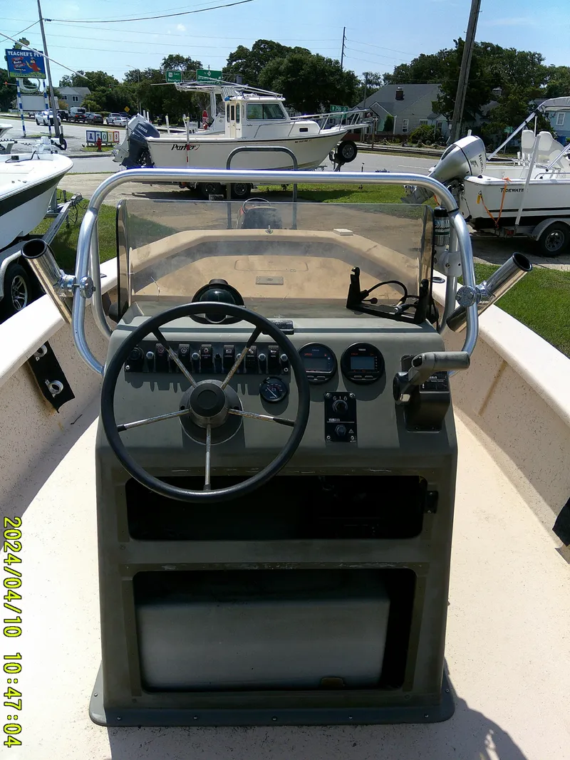 Slide: The Image of 2002 Intruder 20 Skiff boat dashboard with steering wheel and gauges, parked outdoors. - 15