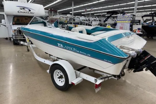 Slide: The Image of 1991 Larson All American 170 boat on trailer in showroom, blue and white design. - 4