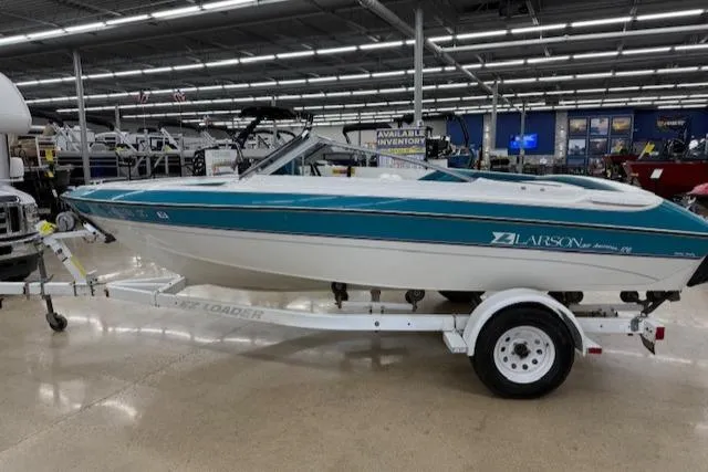 Slide: The Image of 1991 Larson All American 170 boat on trailer in showroom, teal and white design. - 5
