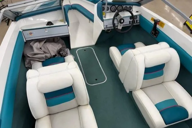 Slide: The Image of 1991 Larson All American 170 boat interior with white and teal seating, dashboard, and steering wheel. - 8