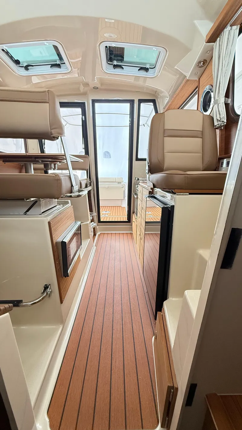 Slide: The Image of 2026 Ranger Tugs R-27 interior with wood flooring and modern seating. - 25