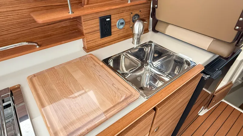Slide: The Image of 2026 Ranger Tugs R-27 galley with wooden countertop and stainless steel sink. - 32
