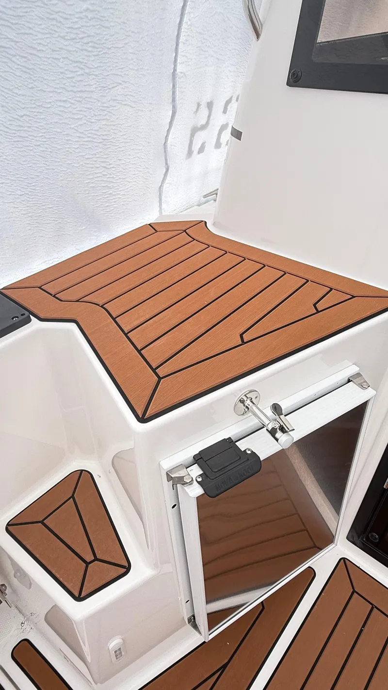 Slide: The Image of 2026 Ranger Tugs R-27 boat interior with teak-style flooring and storage compartment. - 8