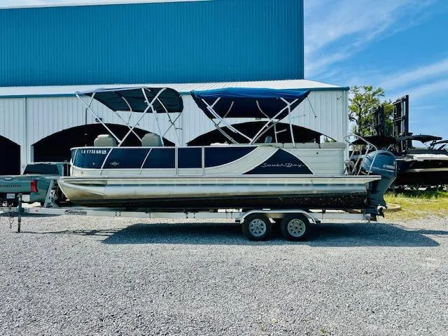 Slide: The Image of 2018 South Bay 525CPTR pontoon boat on trailer, parked outside a blue and white building. - 5