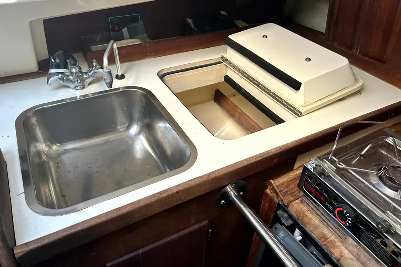 Slide: The Image of 1989 Sabre 30 MKIII yacht galley with sink, stove, and storage compartment. - 13