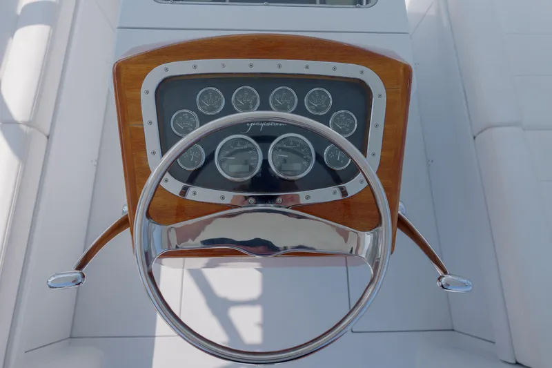 Slide: The Image of Steering wheel and dashboard of 1998 Gamefisherman Enticer boat, featuring classic wood and chrome design. - 10