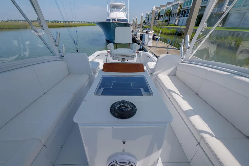 Slide: The Image of 1998 Gamefisherman Enticer boat interior with white seating and navigation equipment at a marina. - 14
