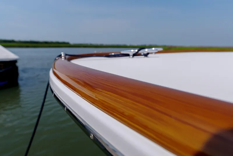 Slide: The Image of Close-up of 1998 Gamefisherman Enticer boat's polished wooden rail on calm water. - 30