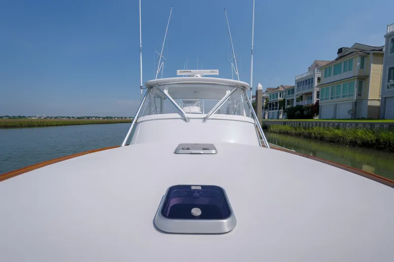 Slide: The Image of 1998 Gamefisherman Enticer boat on calm water near waterfront homes. - 32