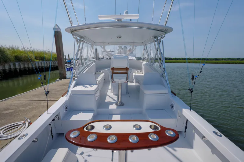 Slide: The Image of 1998 Gamefisherman Enticer boat interior with fishing rods, docked by calm waters. - 36