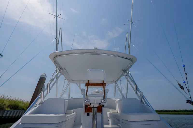 Slide: The Image of 1998 Gamefisherman Enticer boat with white seating and fishing rods under a clear blue sky. - 37