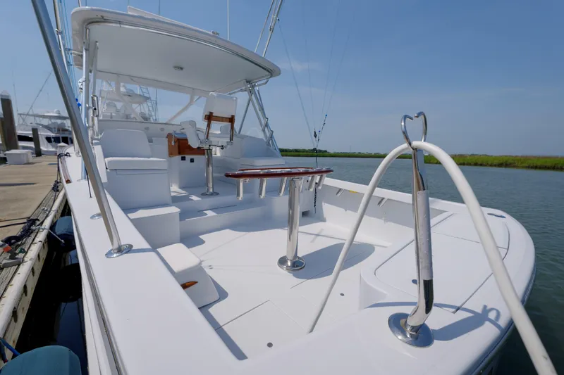 Slide: The Image of 1998 Gamefisherman Enticer boat docked, featuring spacious deck and seating area under clear sky. - 38