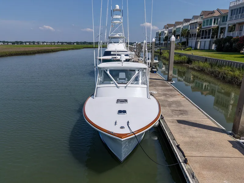 Slide: The Image of 1998 Gamefisherman Enticer yacht docked in a serene marina setting. - 4