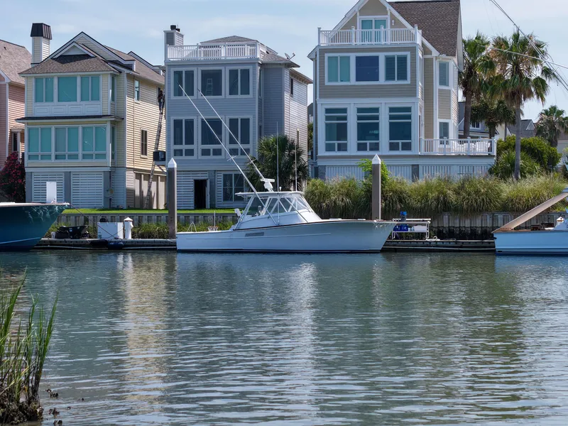 Slide: The Image of 1998 Gamefisherman Enticer boat docked near waterfront homes. - 44