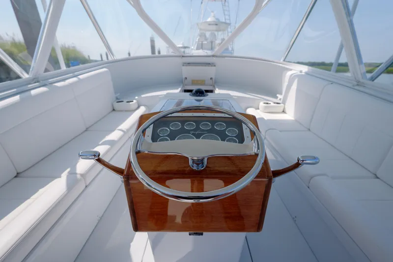 Slide: The Image of 1998 Gamefisherman Enticer boat interior with wooden steering wheel and white seating. - 9