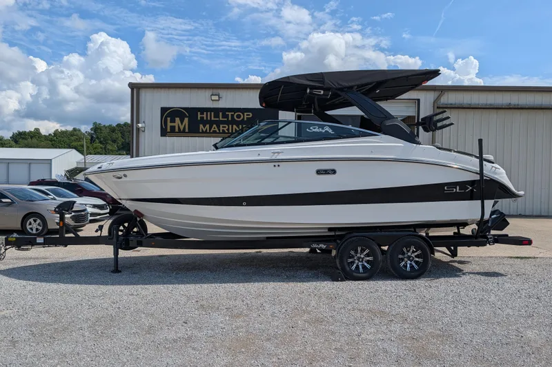 Slide: The Image of 2025 Sea Ray SLX 260 Surf boat on trailer at Hilltop Marine dealership. - 2