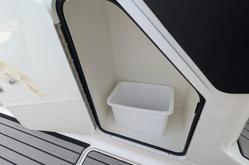 Slide: The Image of Storage compartment with a white bin on the 2025 Sea Ray SLX 260 Surf boat. - 25