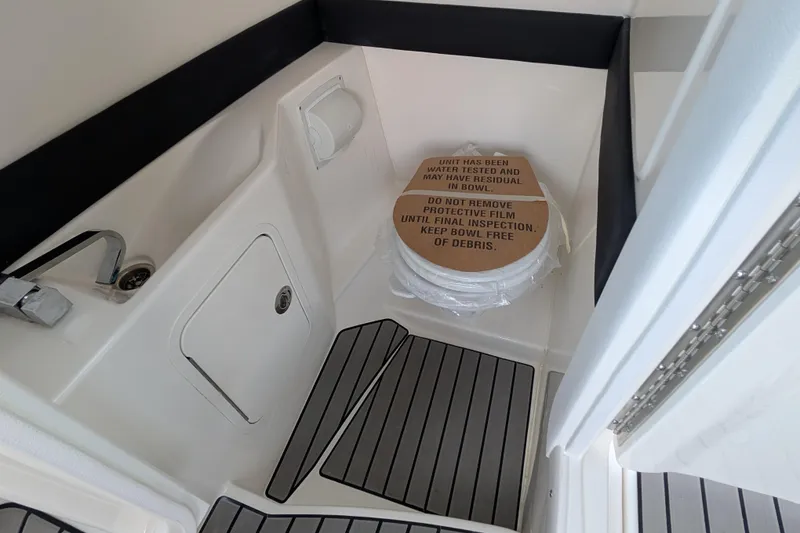 Slide: The Image of 2025 Sea Ray SLX 260 Surf boat interior with sink and toilet, protective film visible. - 26
