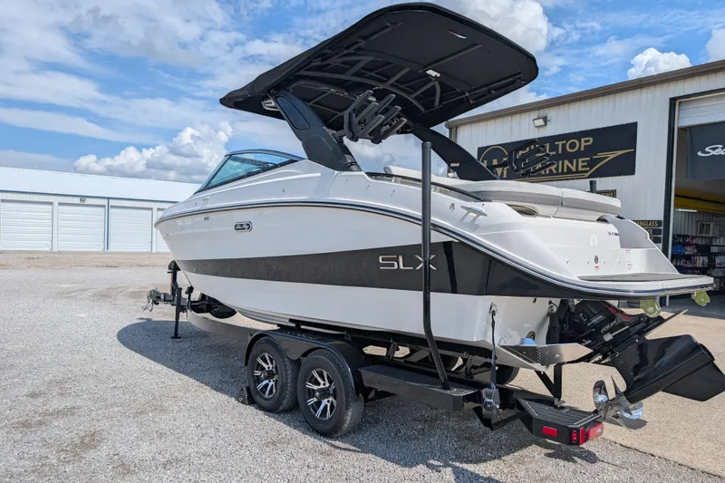 Slide: The Image of 2025 Sea Ray SLX 260 Surf boat on trailer, parked outside marine shop. - 3
